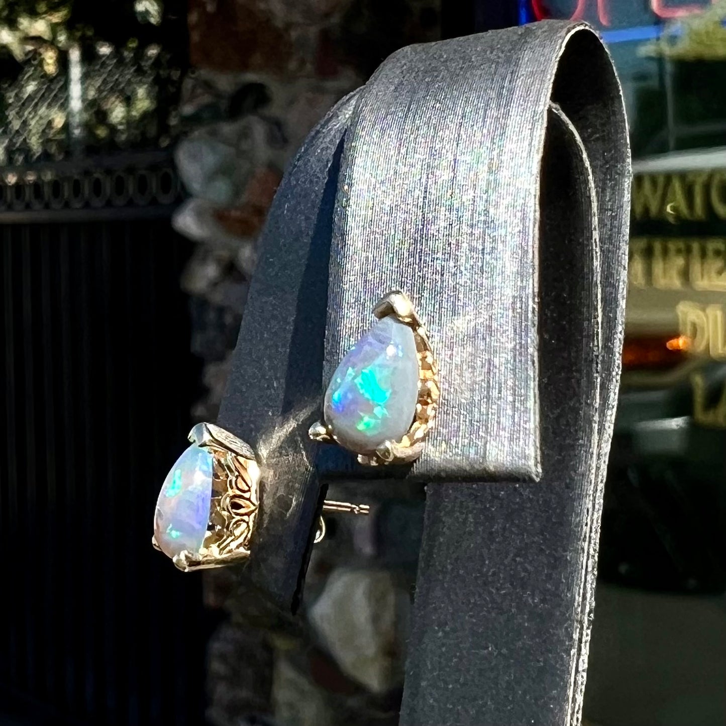 A pair of pear shaped natural black opal stud earrings in filigree style yellow gold baskets.