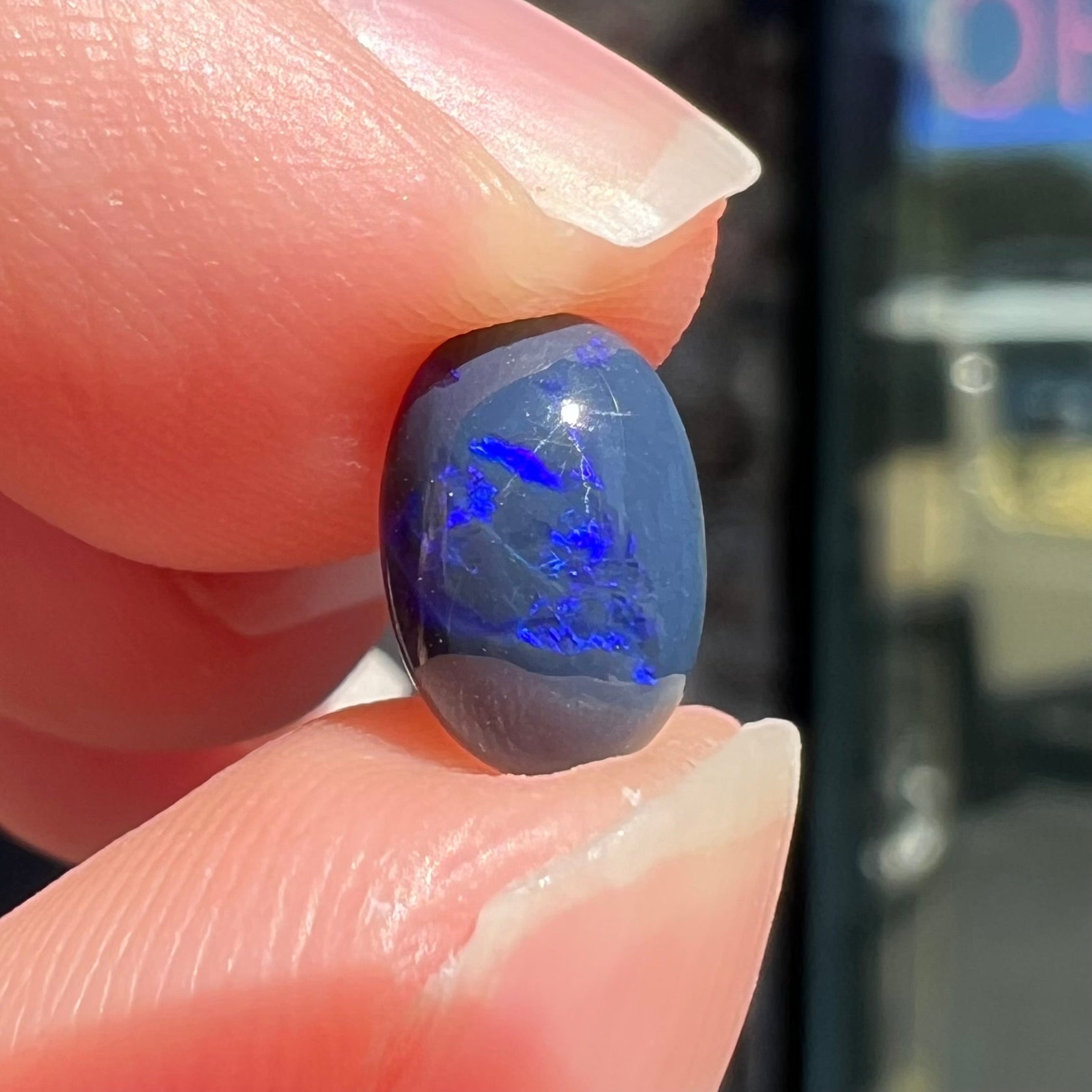 A loose, oval cabochon cut black opal stone from Lightning Ridge, Australia.  The opal has an N2 body tone.