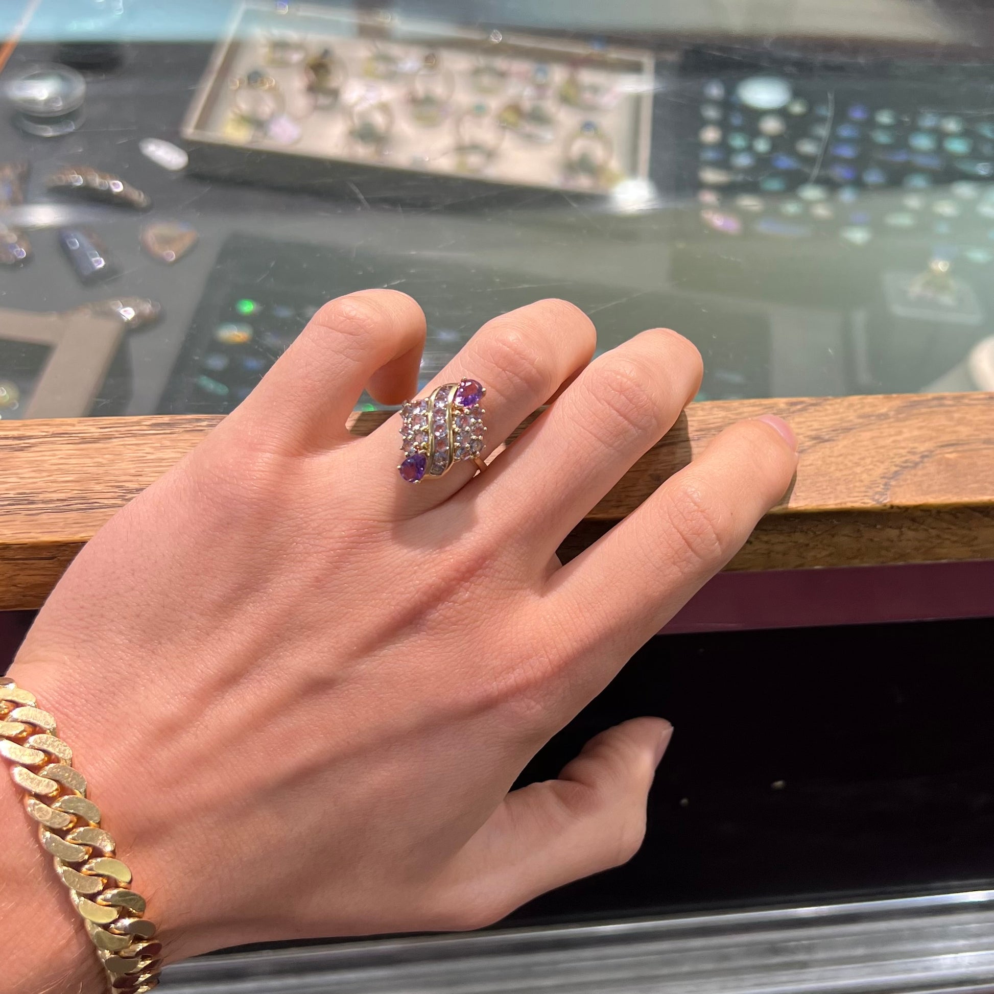 A ladies' gold ring set with a cluster of round tanzanites and two pear shaped amethyst accent stones.