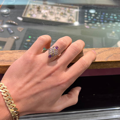 A ladies' gold ring set with a cluster of round tanzanites and two pear shaped amethyst accent stones.
