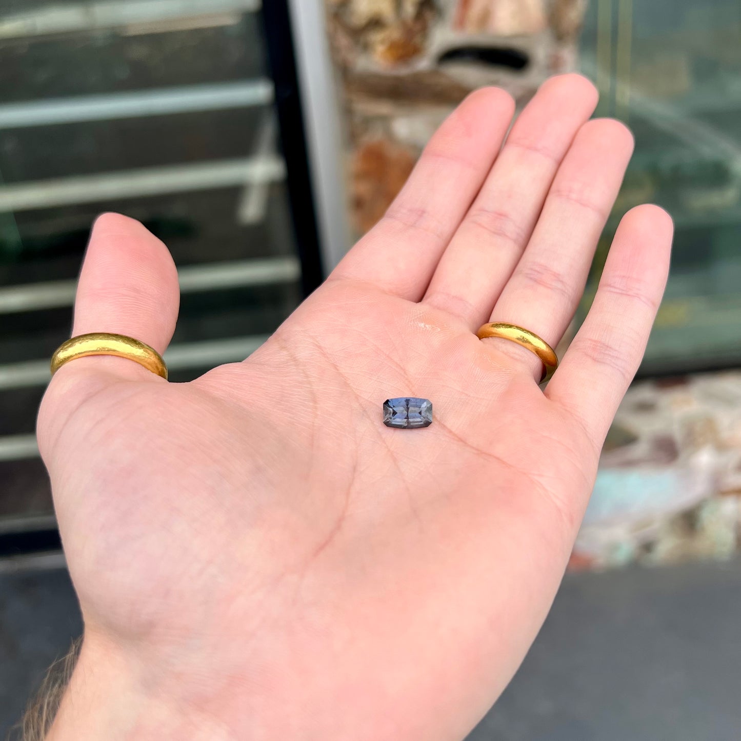 A loose, modified emerald cut, natural color change sapphire stone.  The stone shifts from black to blue to purple to green.