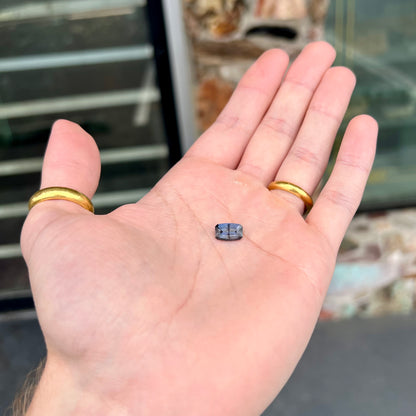 A loose, modified emerald cut, natural color change sapphire stone.  The stone shifts from black to blue to purple to green.