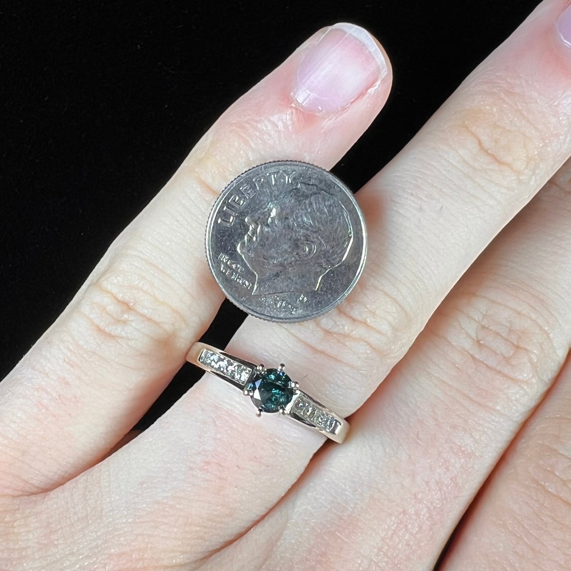 A ladies' white gold engagment ring set with a round brilliant blue diamond and channel set diamond accents.