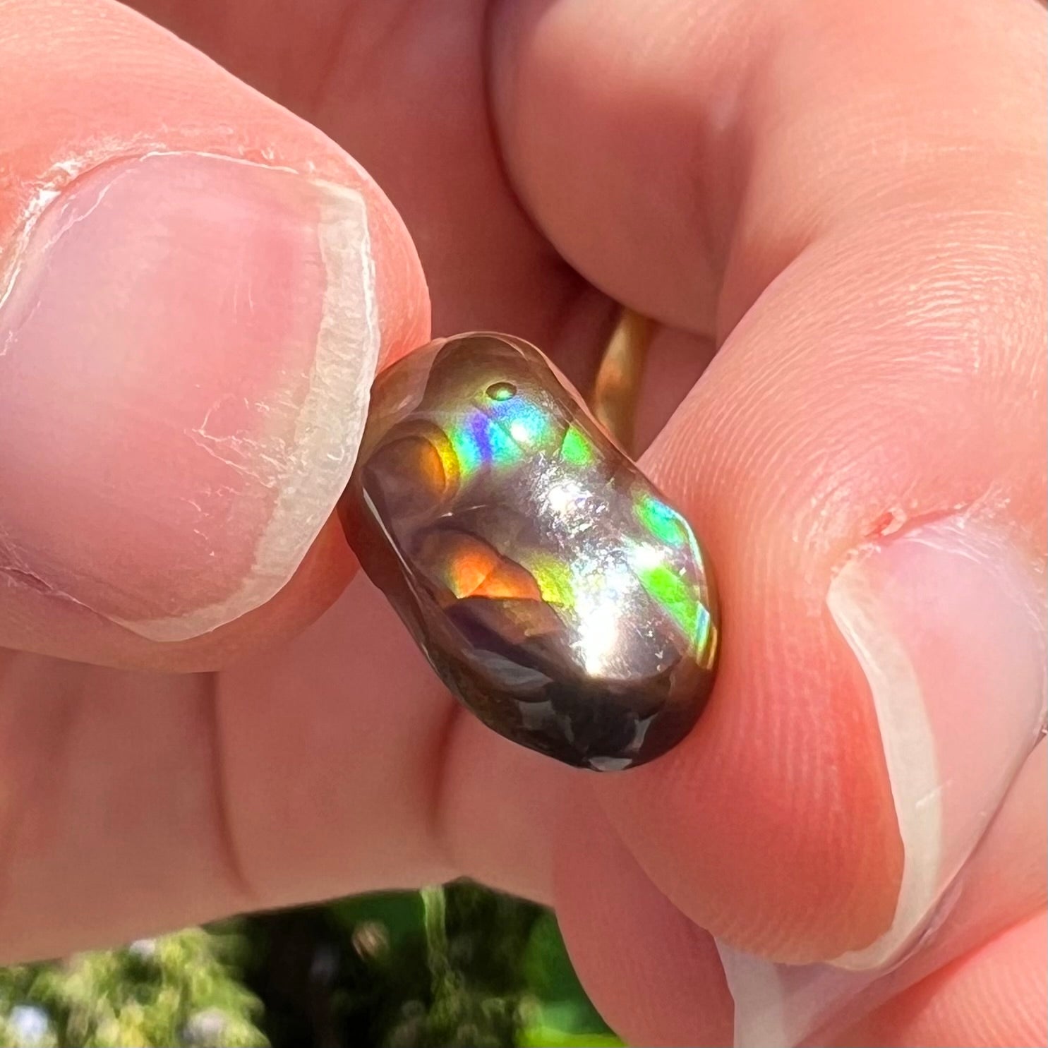 A loose, oval cabochon cut Mexican fire agate stone.  The stone has multi-colored banding with blue overtones.