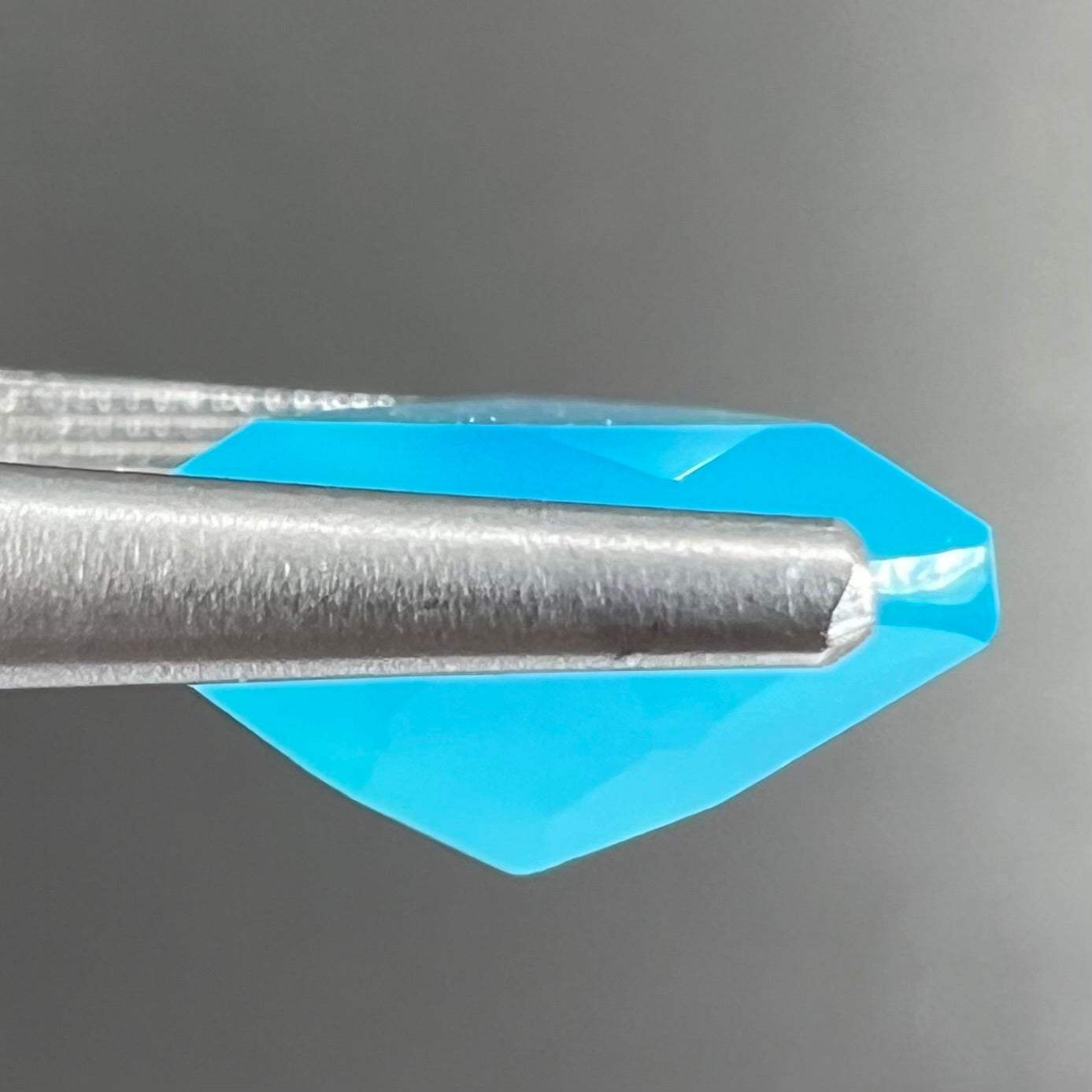 A loose, blue, trillion cut Paraiba chalcedony gemstone.