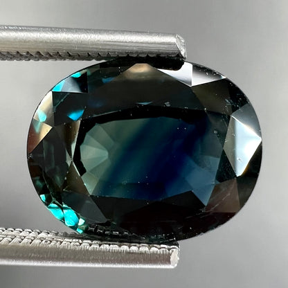 A loose faceted oval cut natural sapphire.  The stone is blue-green color.