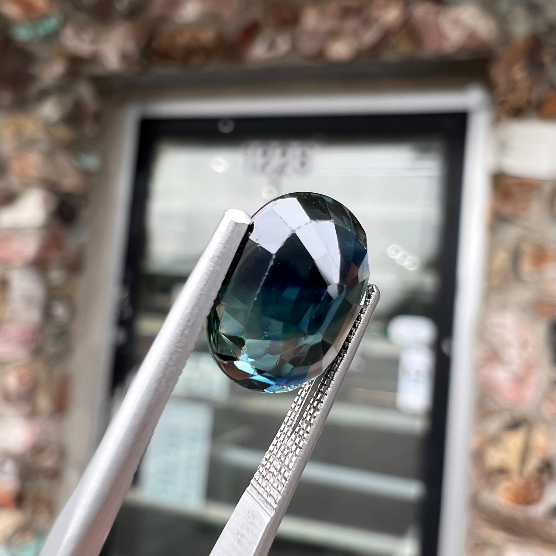 A loose faceted oval cut natural sapphire.  The stone is blue-green color.