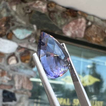 A loose, pear shaped bicolor iolite gemstone.  The stone shows violite purple and silver colors.