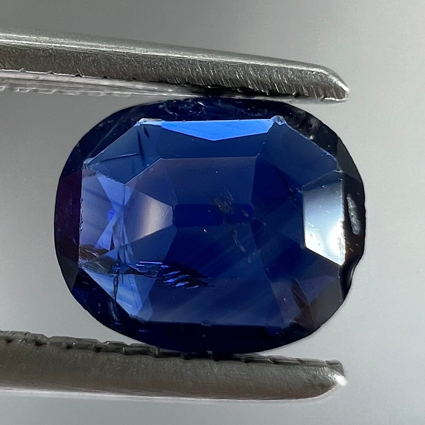 A loose, faceted oval cut dark blue natural sapphire stone.