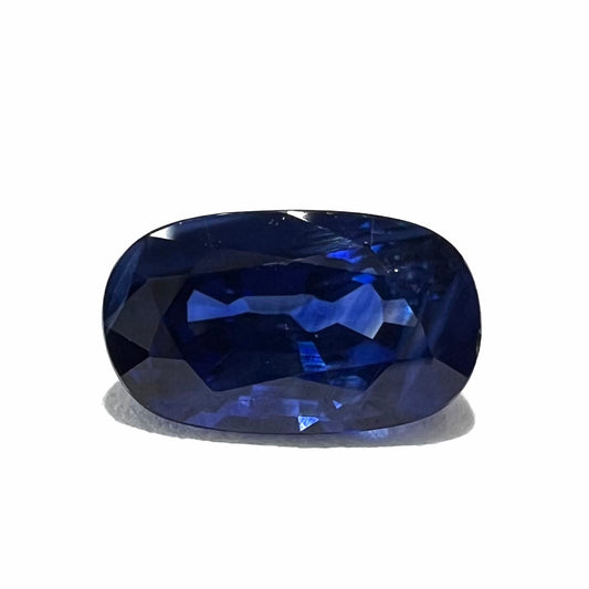 A loose, elongated oval cut blue sapphire gemstone.