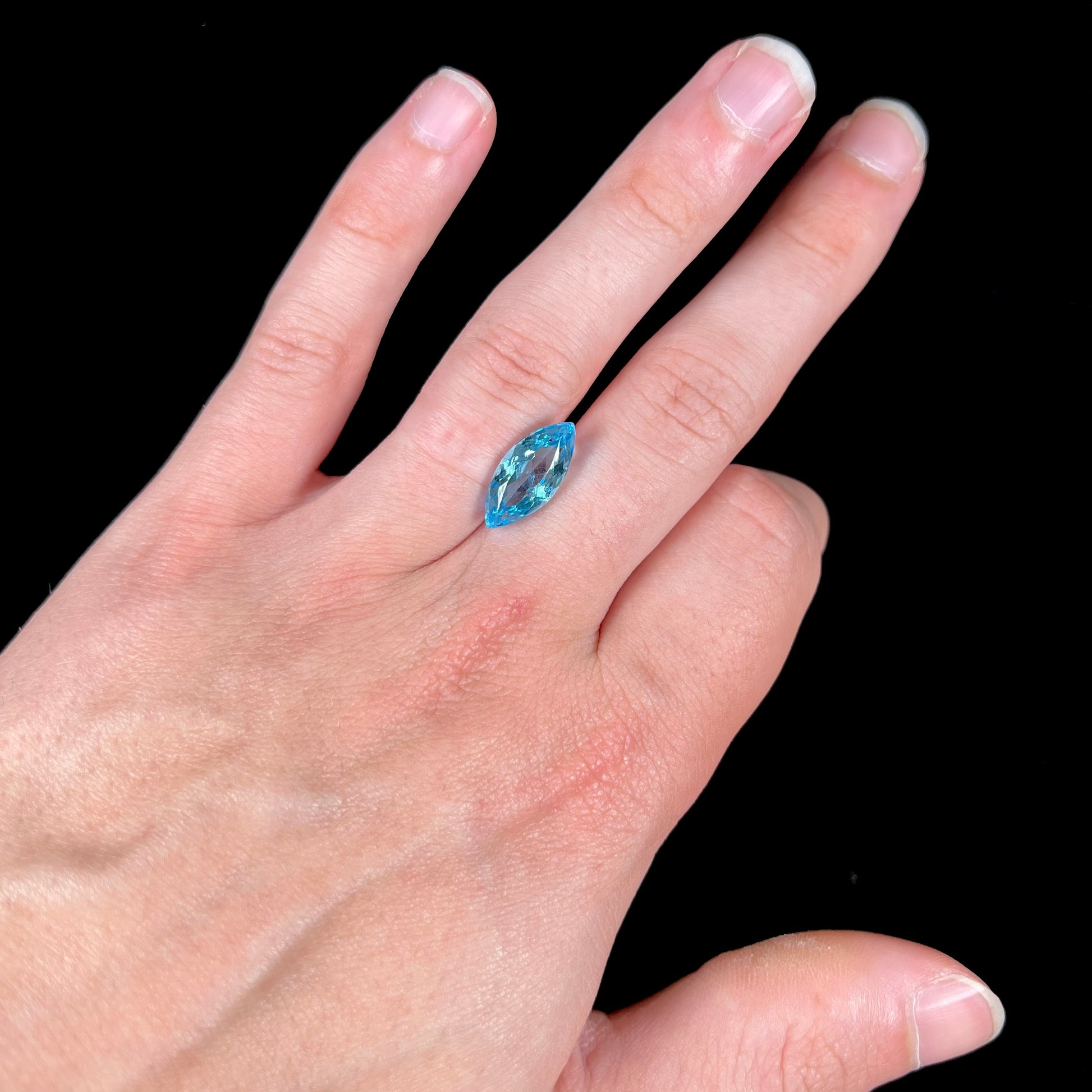 A loose, marquise cut blue topaz gemstone.