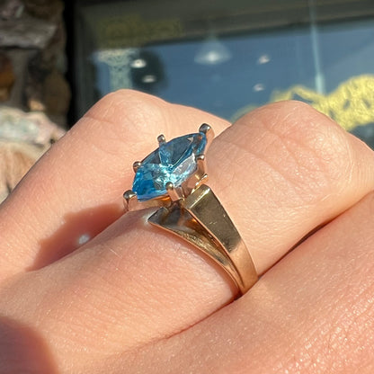 A ladies' estate yellow gold ring, prong set with a marquise cut blue topaz stone.  There are scratches on the shank.