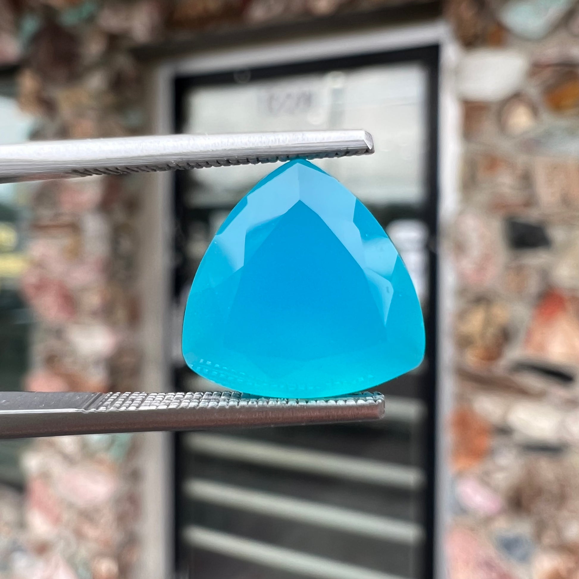A loose, blue, trillion cut Paraiba chalcedony gemstone.