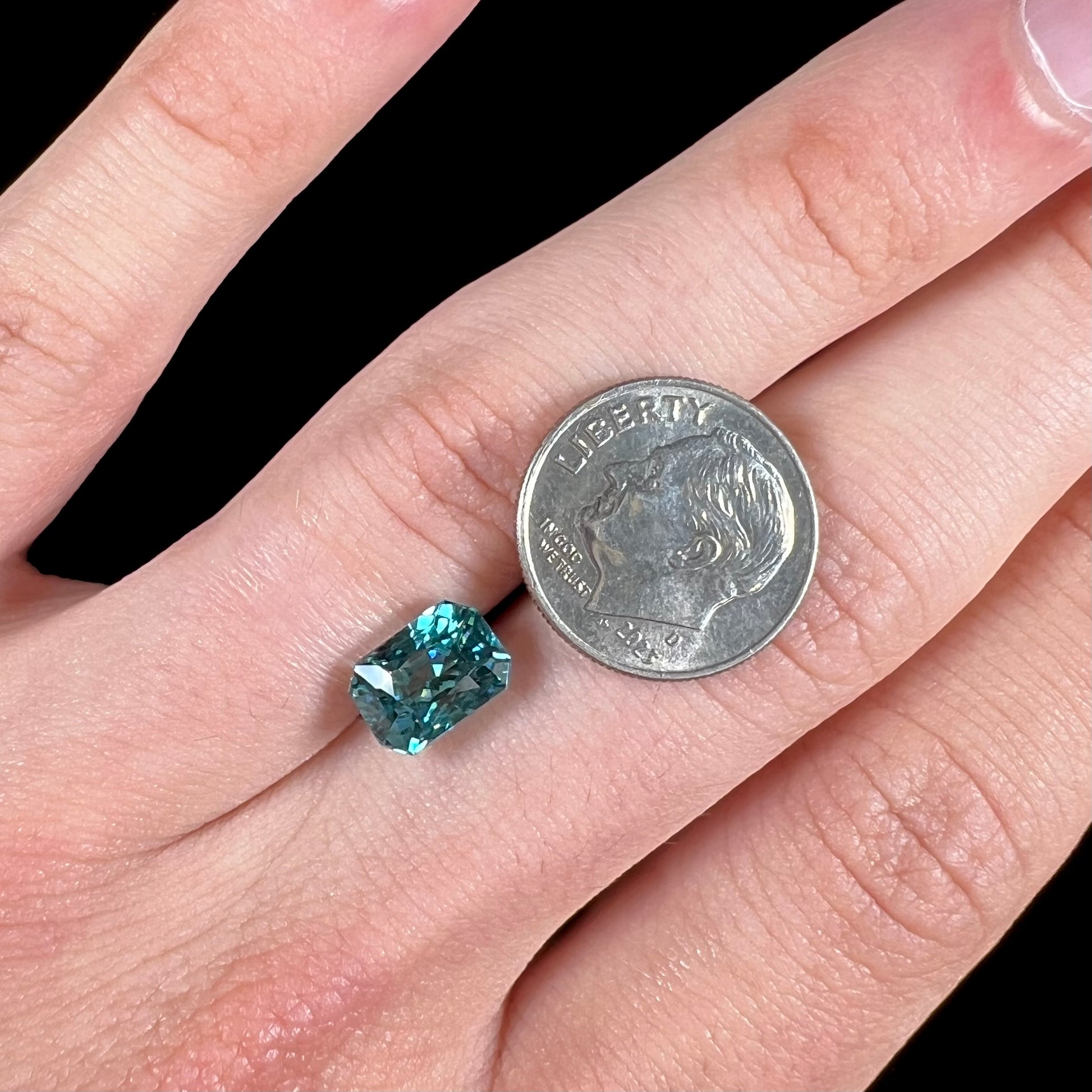 A loose, modified emerald cut blue zircon gemstone.  The stone has a large belly.