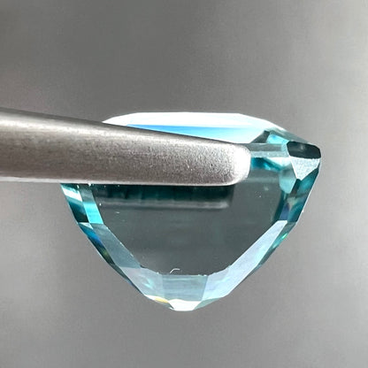 A loose, modified emerald cut blue zircon gemstone.  The stone has a large belly.