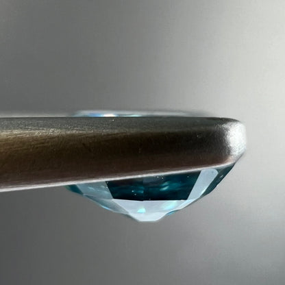 A loose, faceted oval cut blue zircon gemstone.