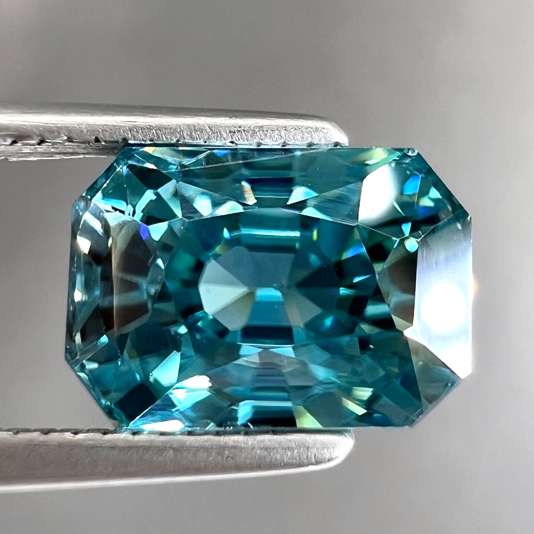 A loose, modified emerald cut blue zircon gemstone.  The stone has a large belly.