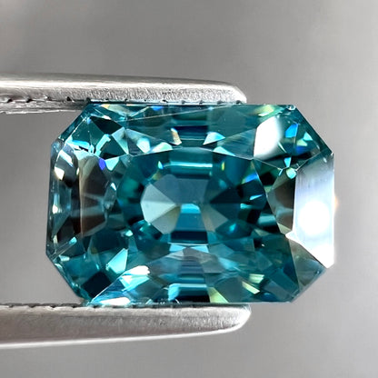 A loose, modified emerald cut blue zircon gemstone.  The stone has a large belly.