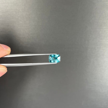 A loose, modified emerald cut blue zircon gemstone.  The stone has a large belly.