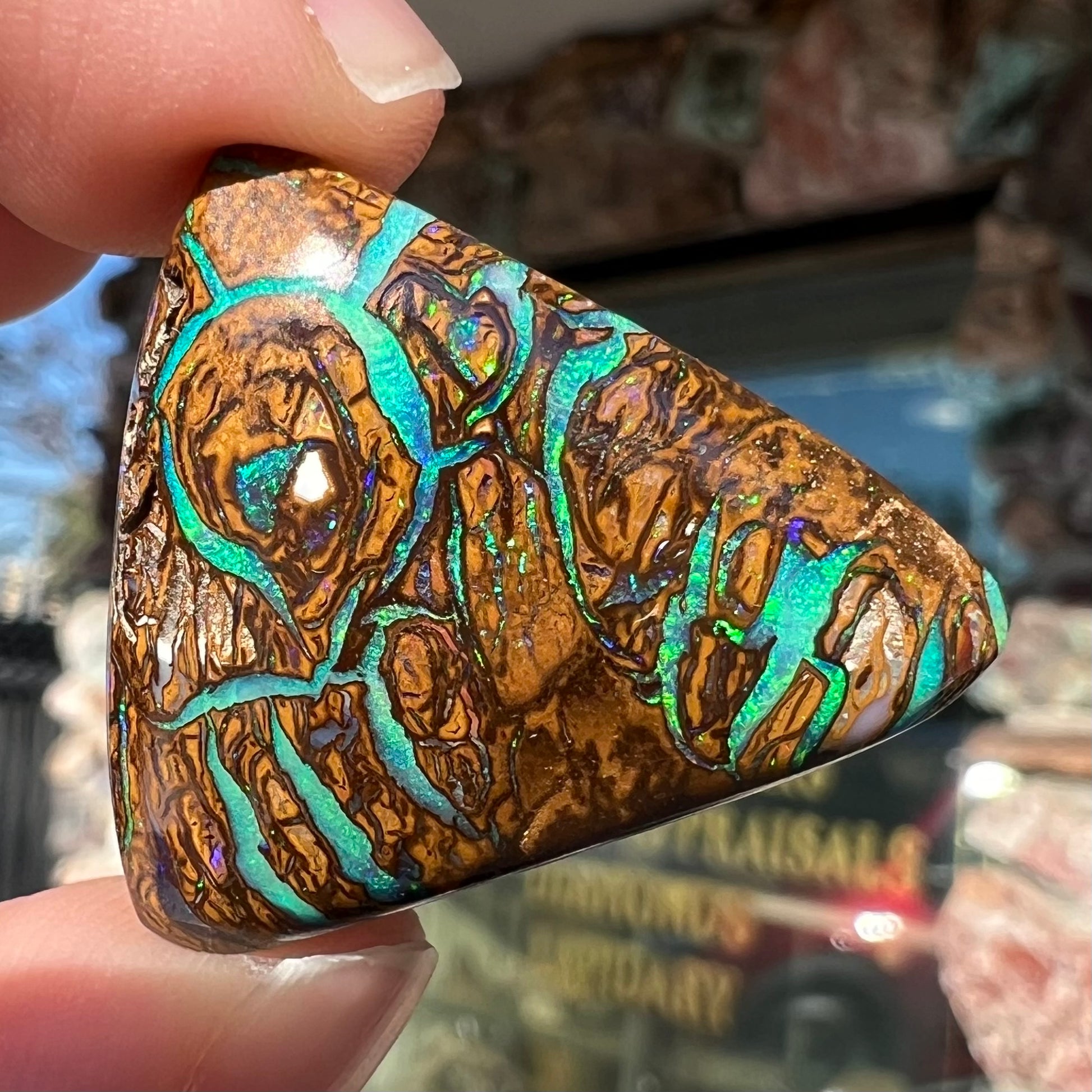 A triangle shaped Koroit boulder opal.  The stone has blue veins of opal running through it.