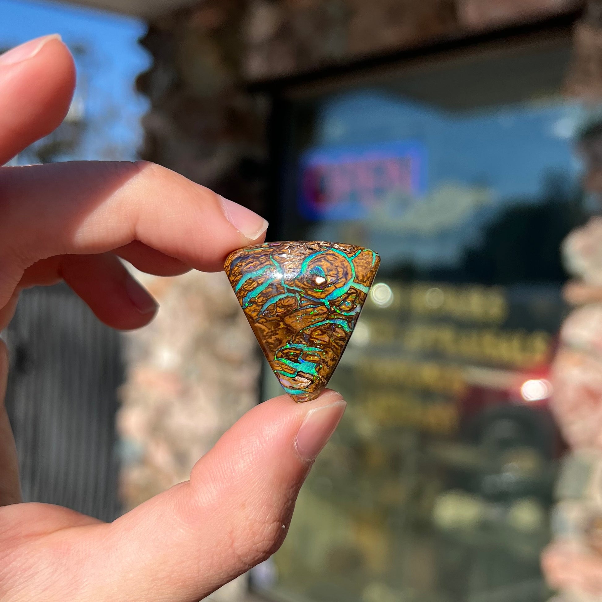 A triangle shaped Koroit boulder opal.  The stone has blue veins of opal running through it.