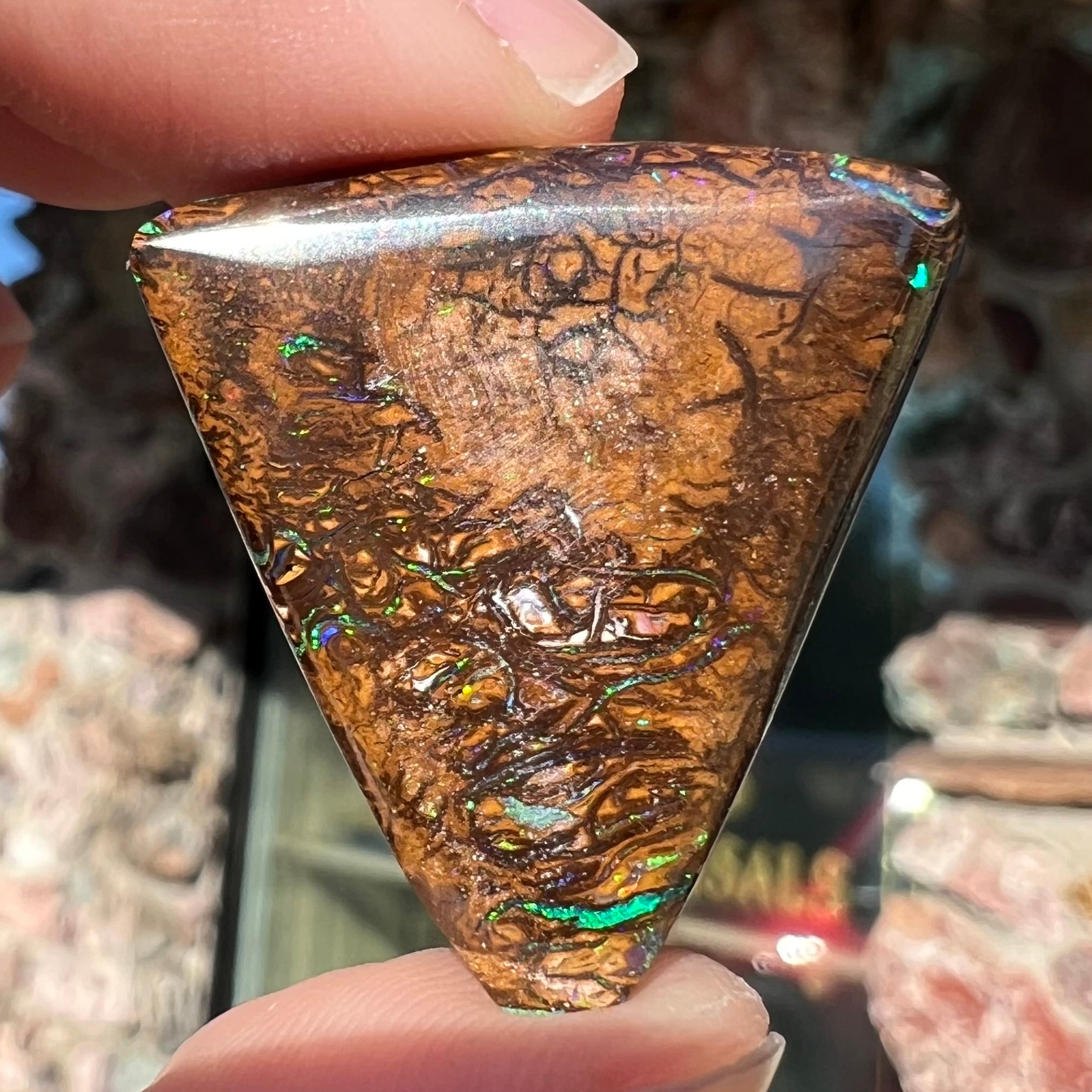 A triangle shaped Koroit boulder opal.  The stone has blue veins of opal running through it.