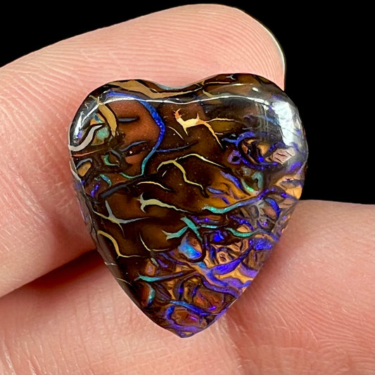 A heart shaped boulder opal stone with purple veins.