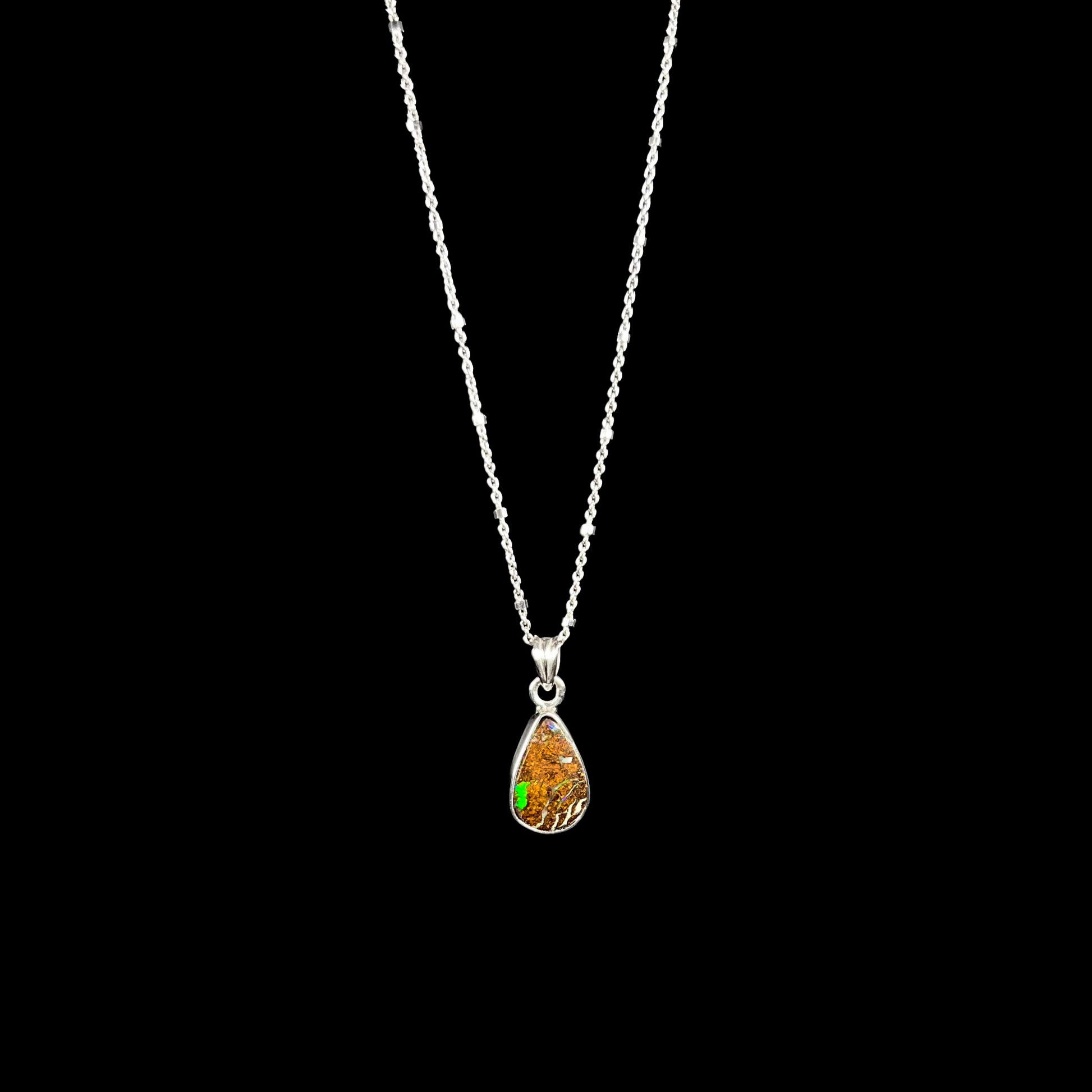 A sterling silver necklace bezel set with a natural Australian boulder opal stone.  The stone is brown with bright green and blue flashes.
