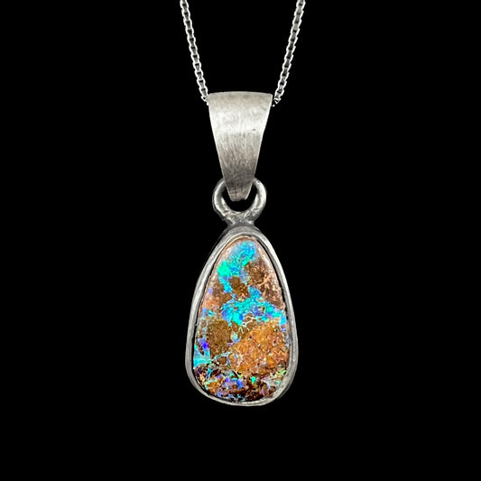A handmade, satin finish sterling silver pendant set with a drop shaped boulder opal stone.