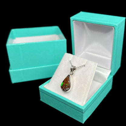 A sterling silver necklace bezel set with a natural Australian boulder opal stone.  The stone is brown with bright green and blue flashes.