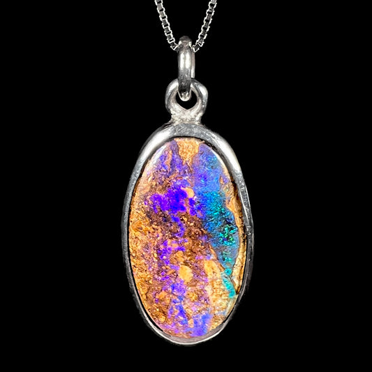 A handmade sterling silver pendant bezel set with an oval cut pipe boulder opal stone.
