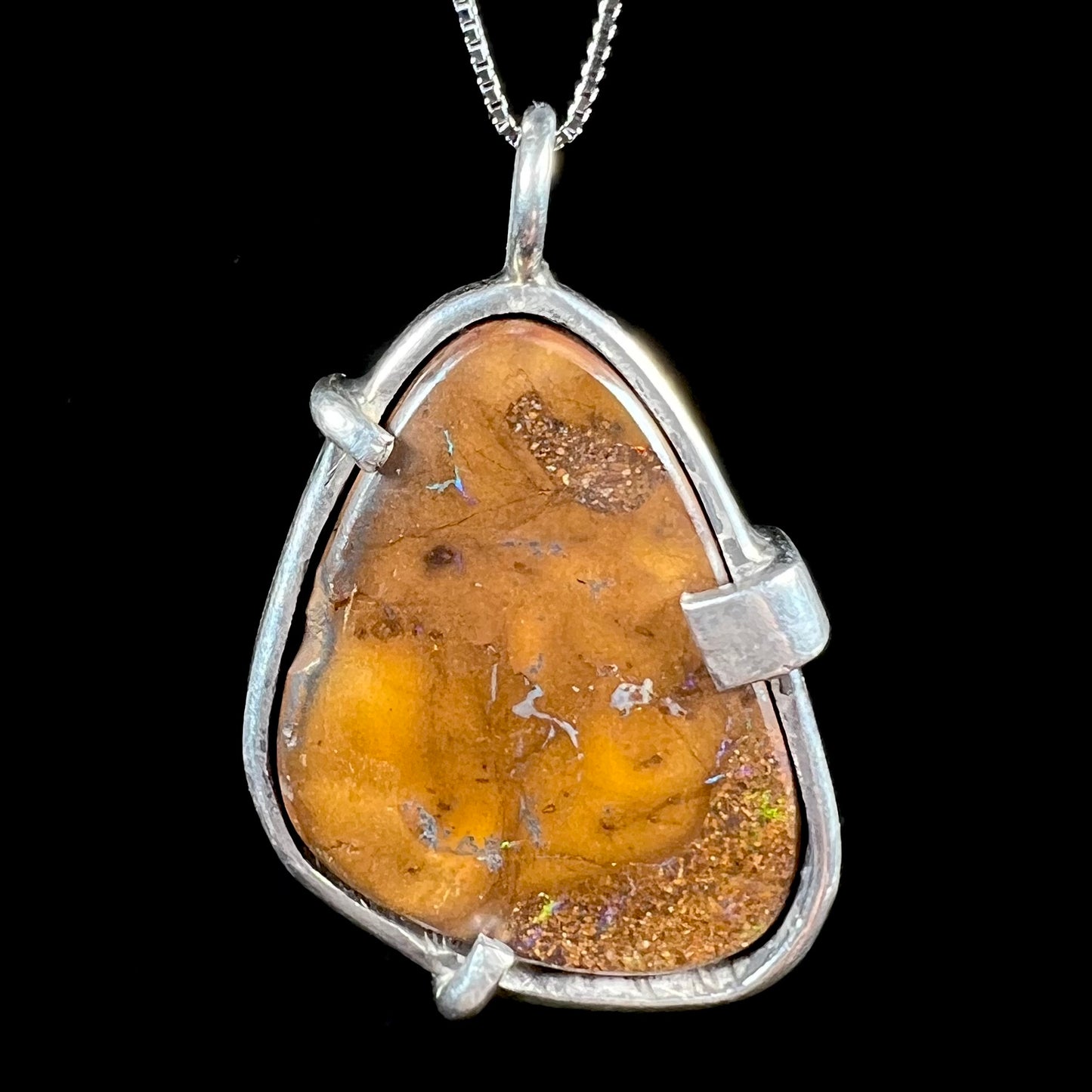 A handmade sterling silver pendant bezel and prong set with a natural boulder opal stone.