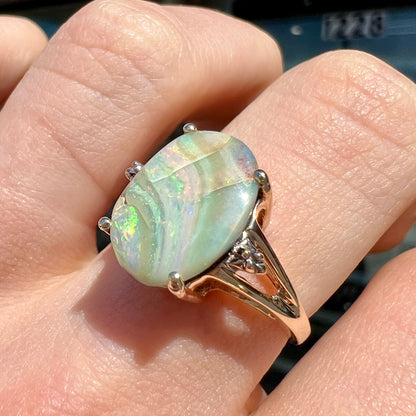 A ladies' Australian boulder opal ring set in yellow gold with diamond accents.  The opal shimmers green and pink and has fissure inclusions.