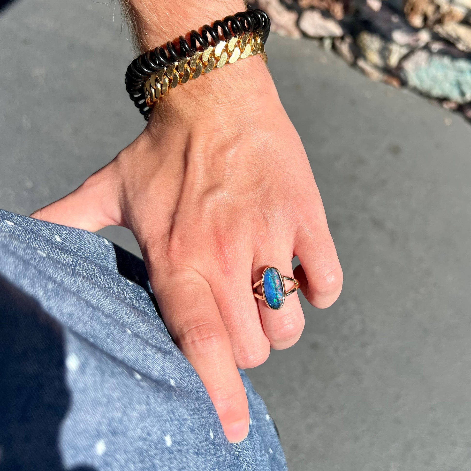 A ladies' yellow gold split shank solitaire ring set with a natural Australian black boulder opal.