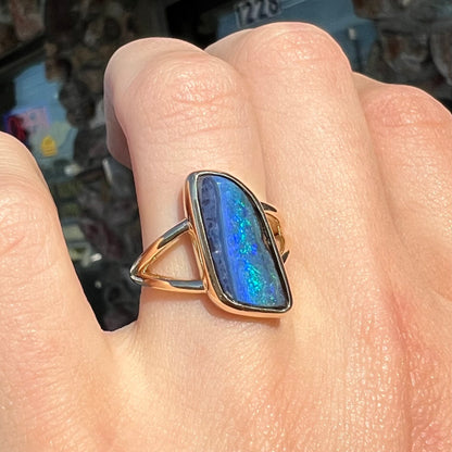 A ladies' split shank gold ring bezel set with a natural, Australian black boulder opal.