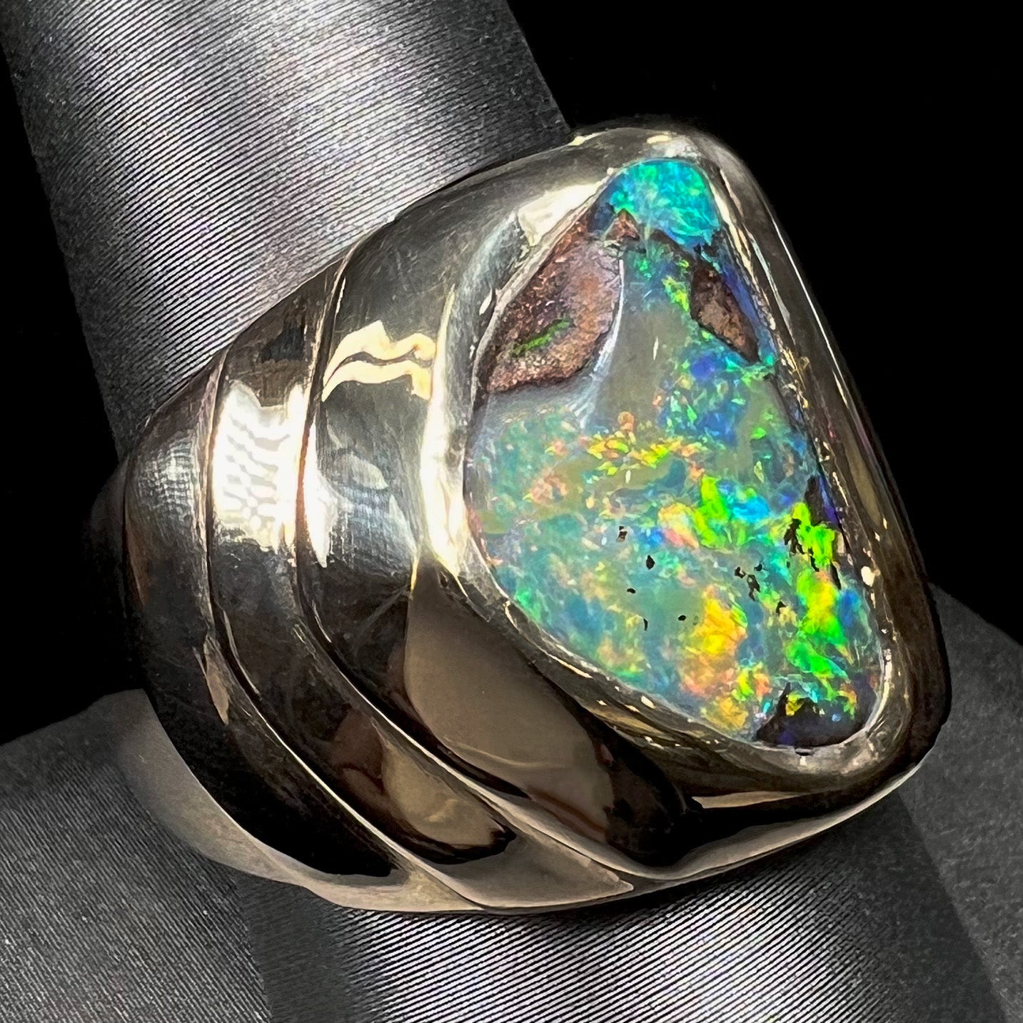 A men's yellow gold solitaire ring set with a triangular shaped natural boulder opal.