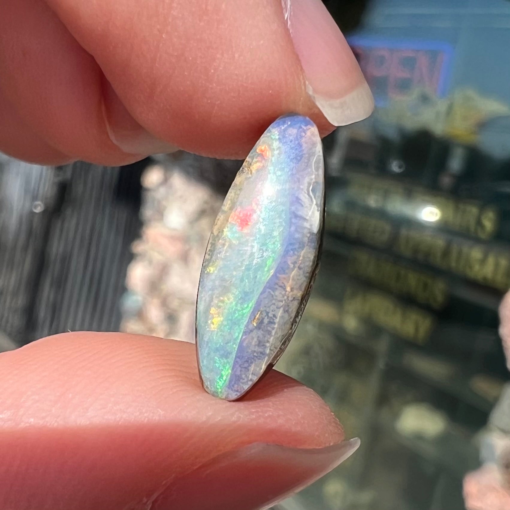 A loose, marquise cut boulder opal from Quilpie, Australia.  The opal has green and red wave patterns.