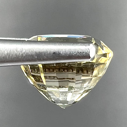 A loose, round brilliant cut citrine gemstone.  The stone is light yellow color.