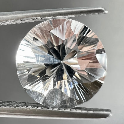 A round brilliant cut petalite gemstone.  The stone is colorless.