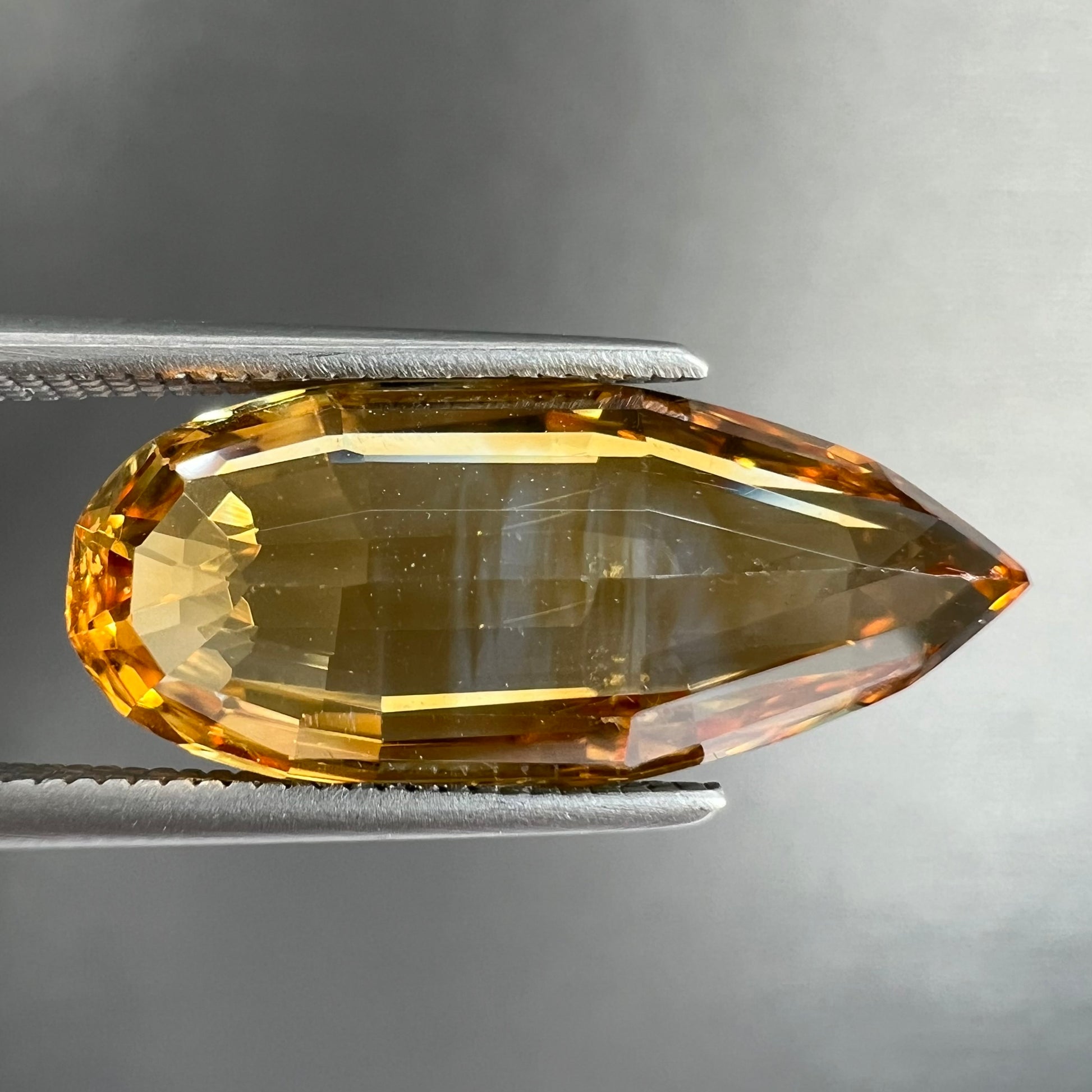 A loose, faceted briolette cut citrine gemstone.