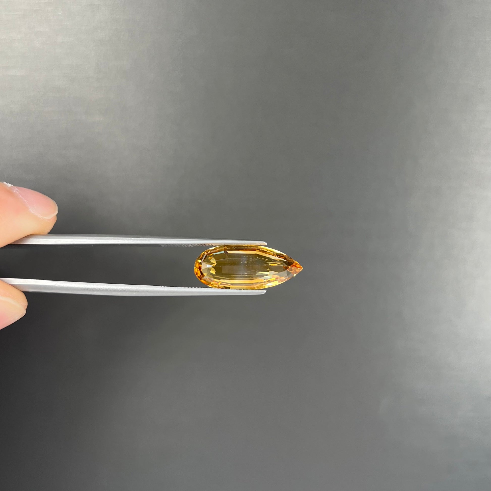 A loose, faceted briolette cut citrine gemstone.
