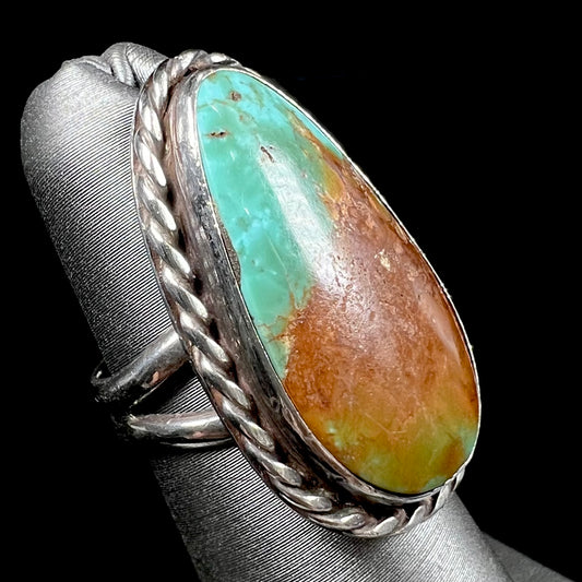 A sterling silver ring made with a rope bezel design and set with a green and brown Royston turquoise stone.