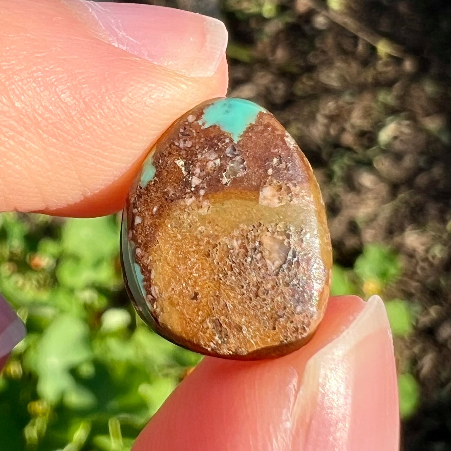 A freeform pear shaped Royston turquoise stone.  The stone is predominantly brown matrix with green turquoise around the edges.