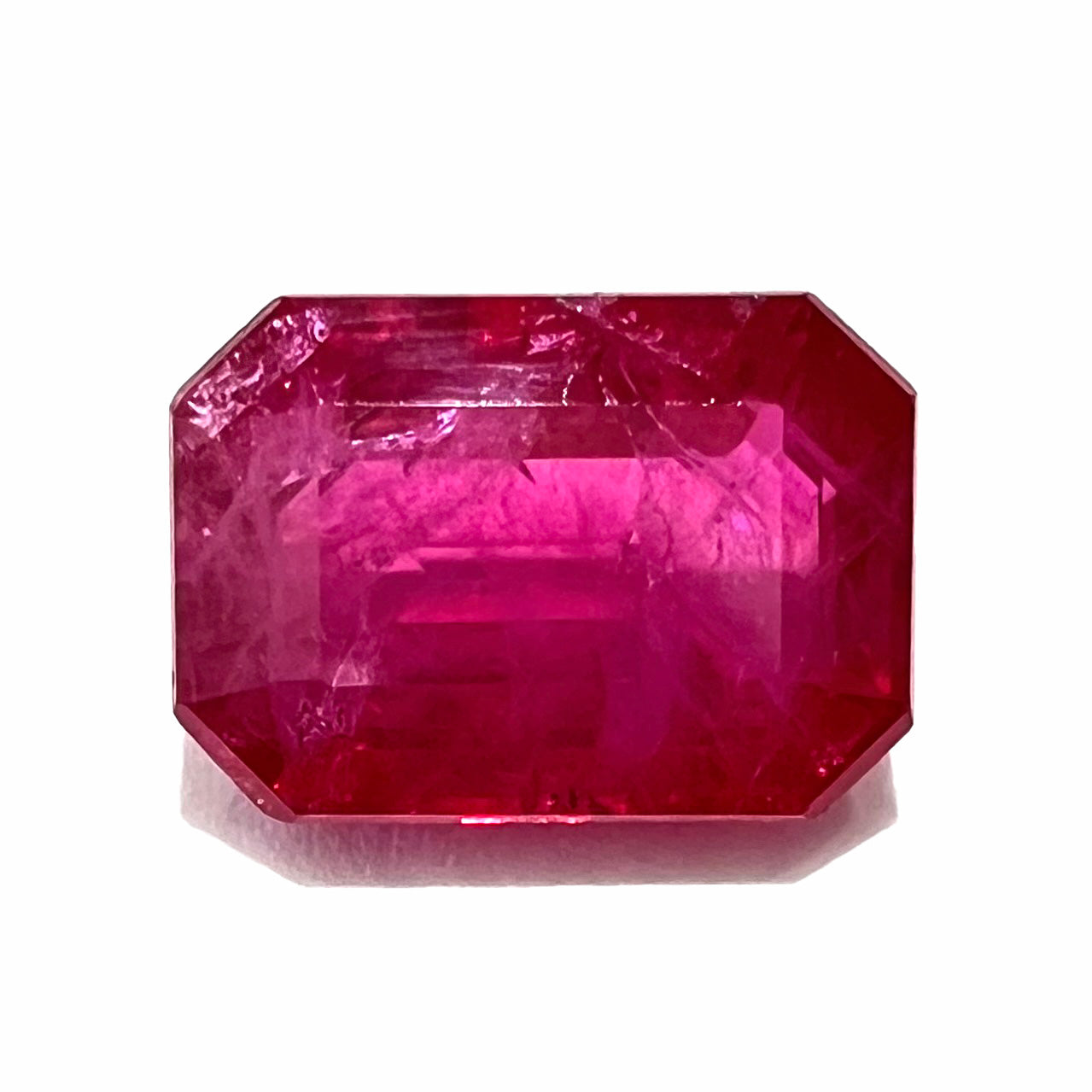 An emerald cut Burma ruby gemstone.  The stone is loose and a pinkish red color.