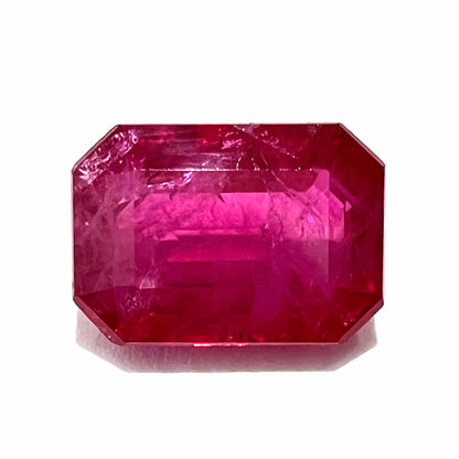 An emerald cut Burma ruby gemstone.  The stone is loose and a pinkish red color.