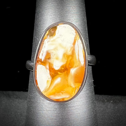 An adjustable sterling silver solitaire ring set with a cabochon cut butterscotch amber stone.