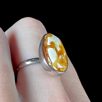 An adjustable sterling silver solitaire ring set with a cabochon cut butterscotch amber stone.