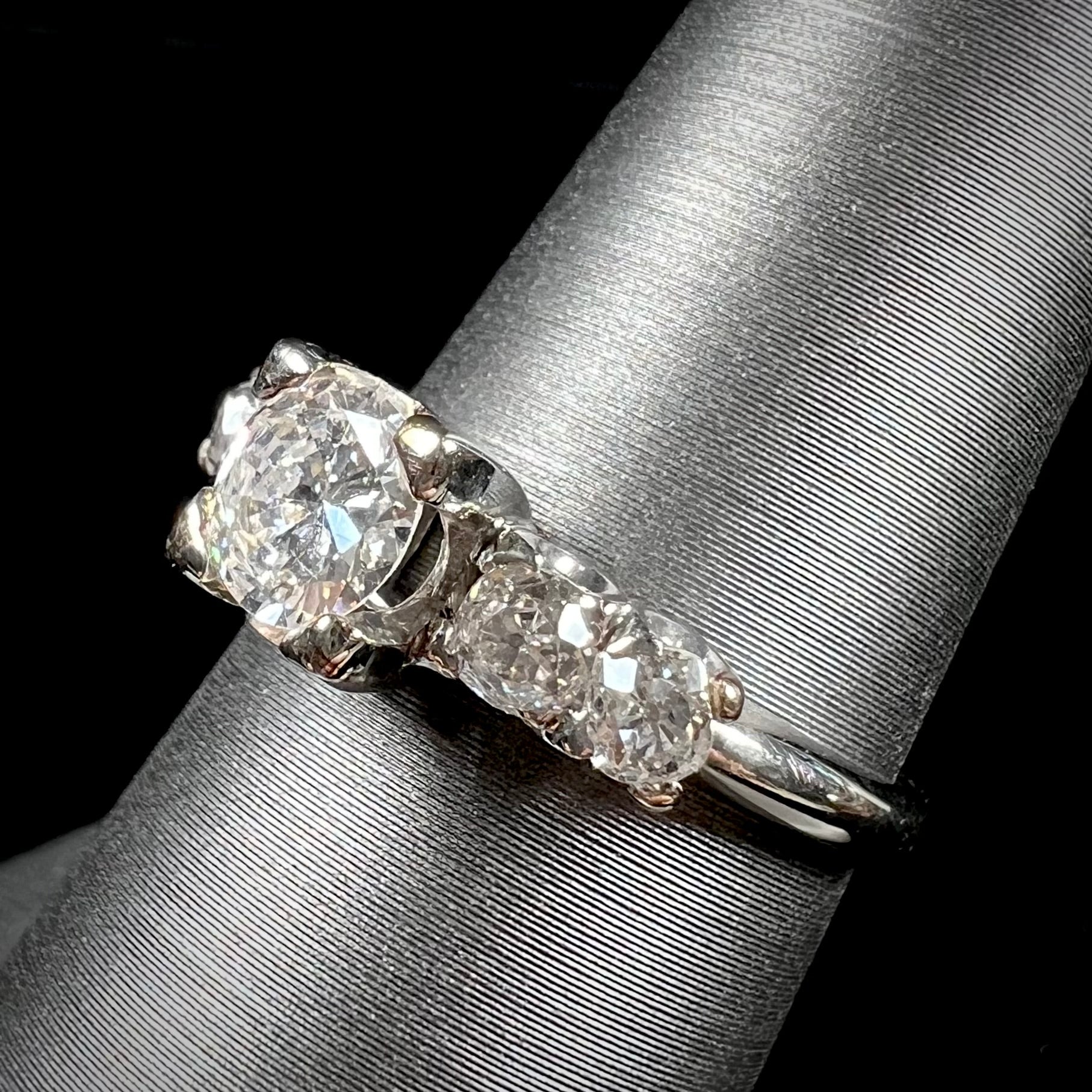 A ladies' 1800's antique white gold diamond ring.  The center stone is an Early American Cut diamond, and the accent stones are Old Mine Cut diamonds.