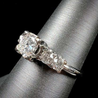 A ladies' 1800's antique white gold diamond ring.  The center stone is an Early American Cut diamond, and the accent stones are Old Mine Cut diamonds.