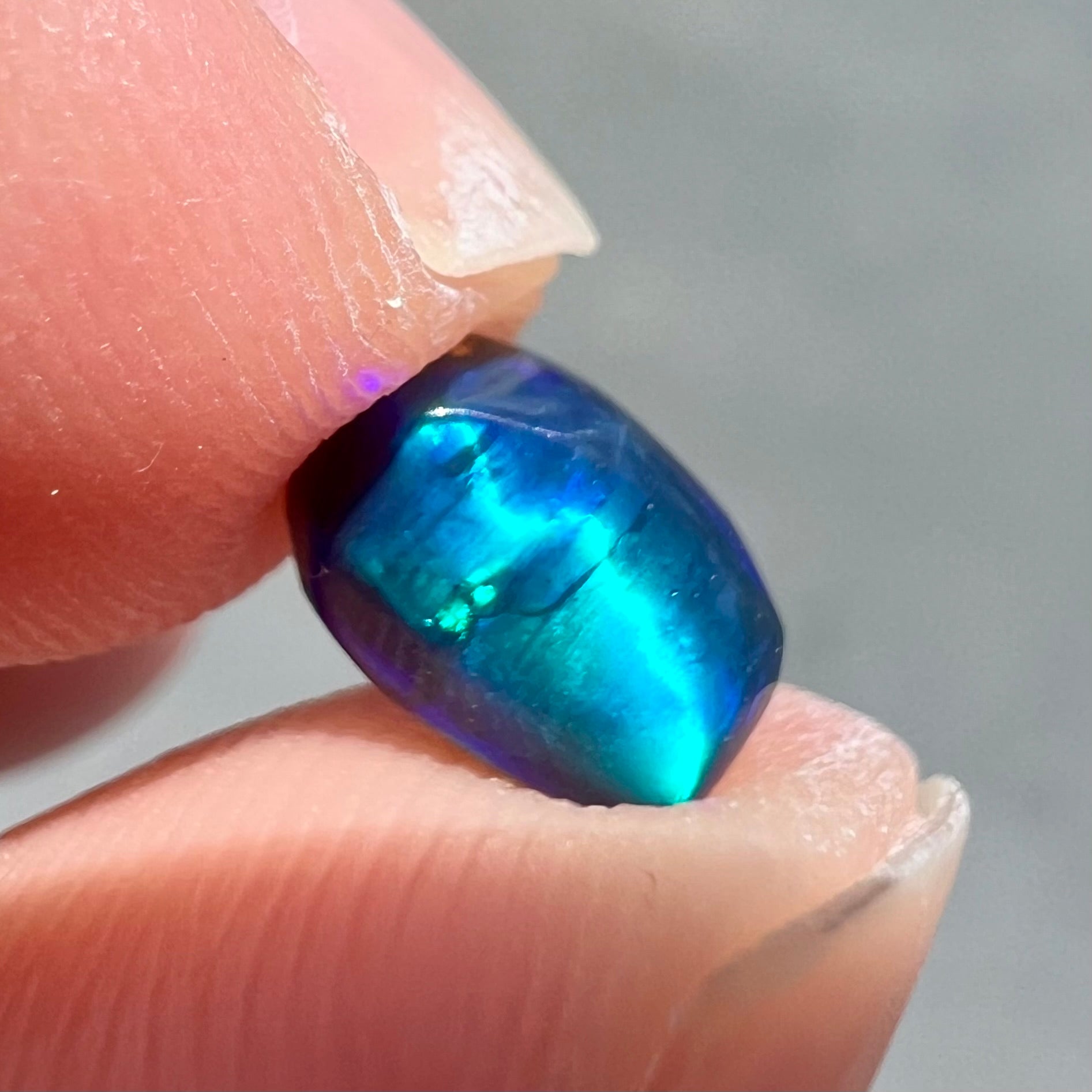 A loose black opal from Lightning Ridge, Australia.  The opal displays a blue cat's eye pattern.